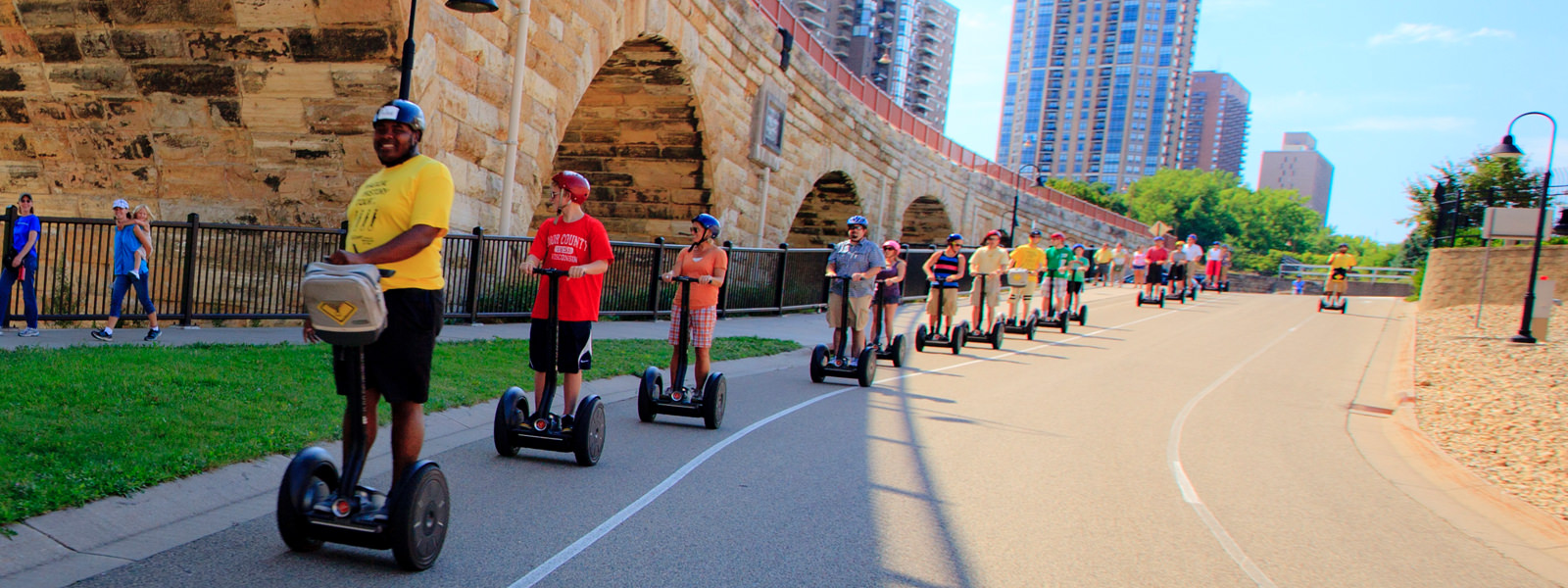 Segway group exploring the Minneapolis riverfront beside a stone bridge